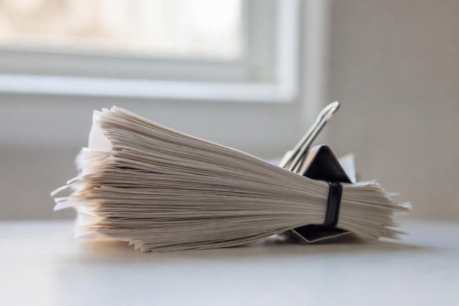 A thick clipped stack of identical paper receipts standing on a desk