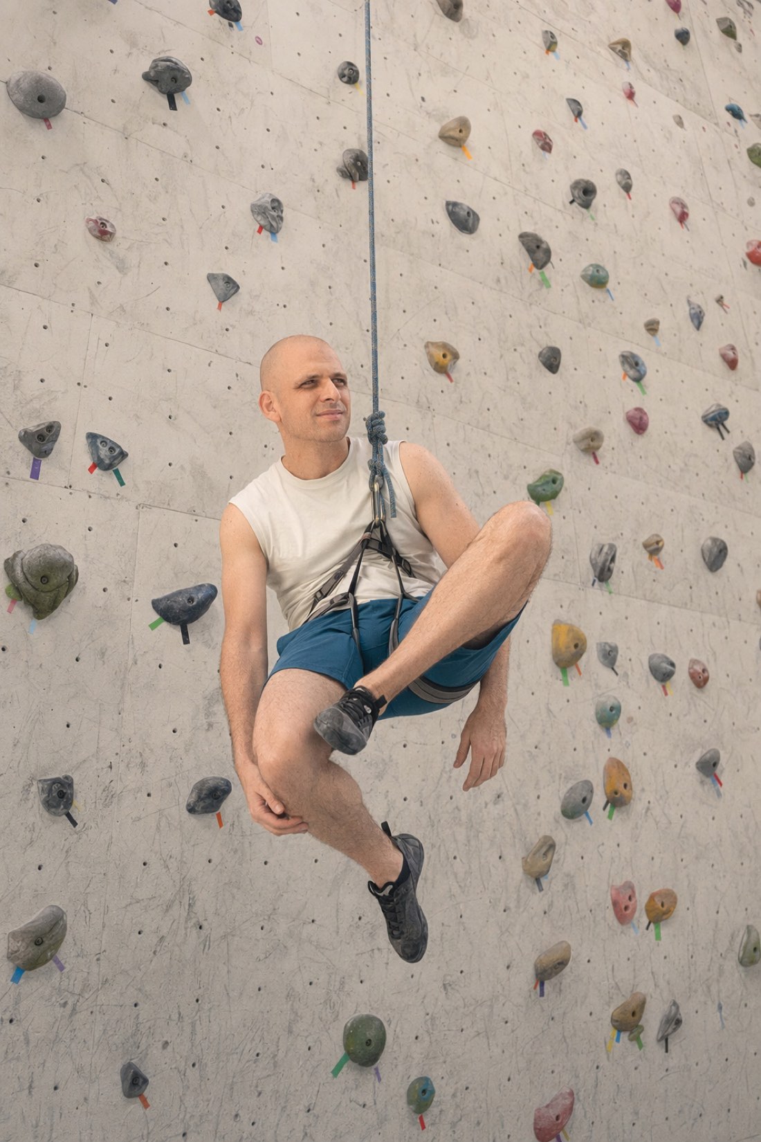 Man resting in a climbing harness, hanging off the wall