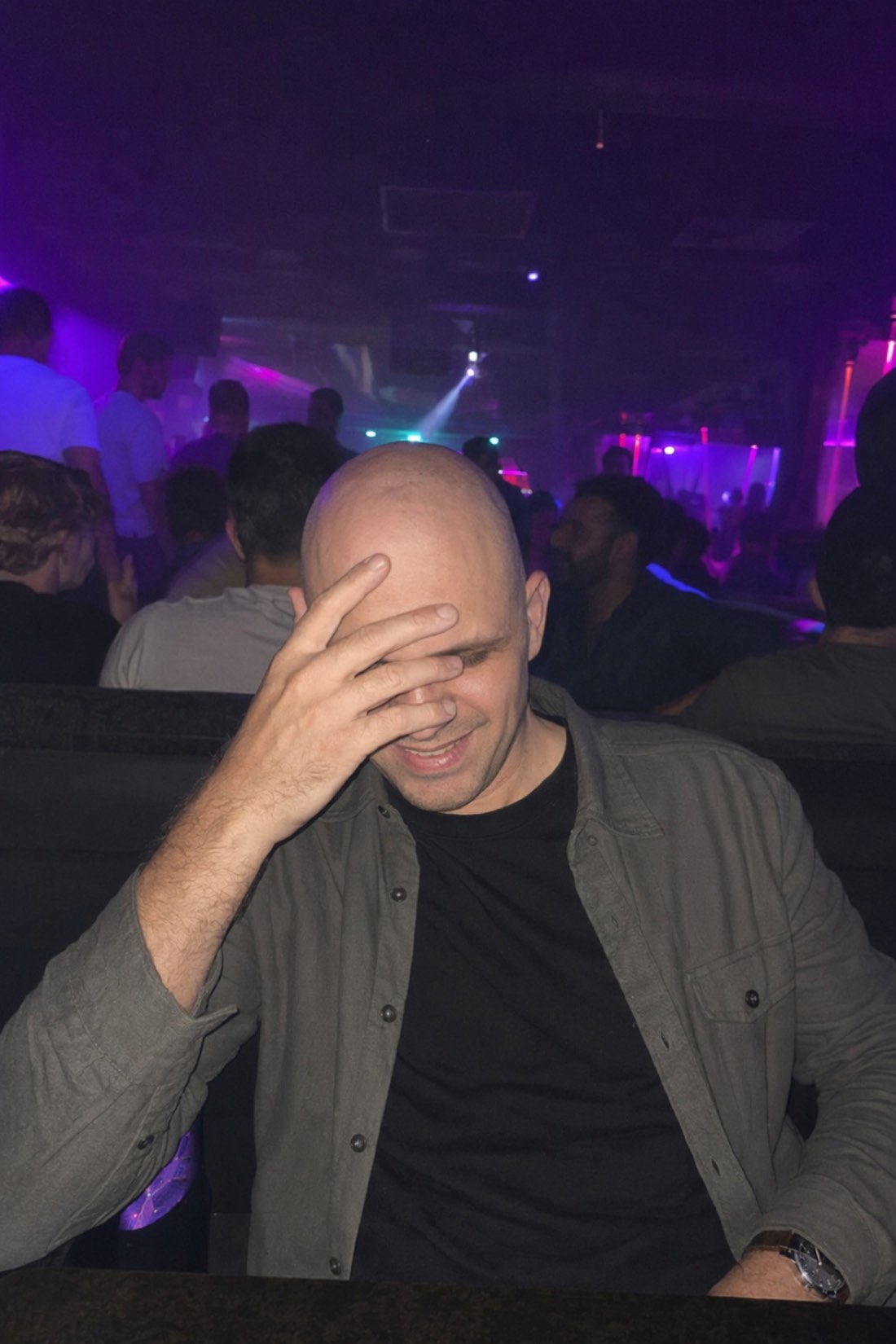 Man laughing behind his hand at a nightclub